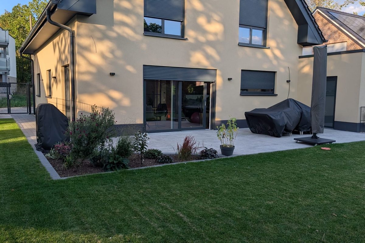 Terrasse mit Pflanzfläche und sauberem Rasenanschluss